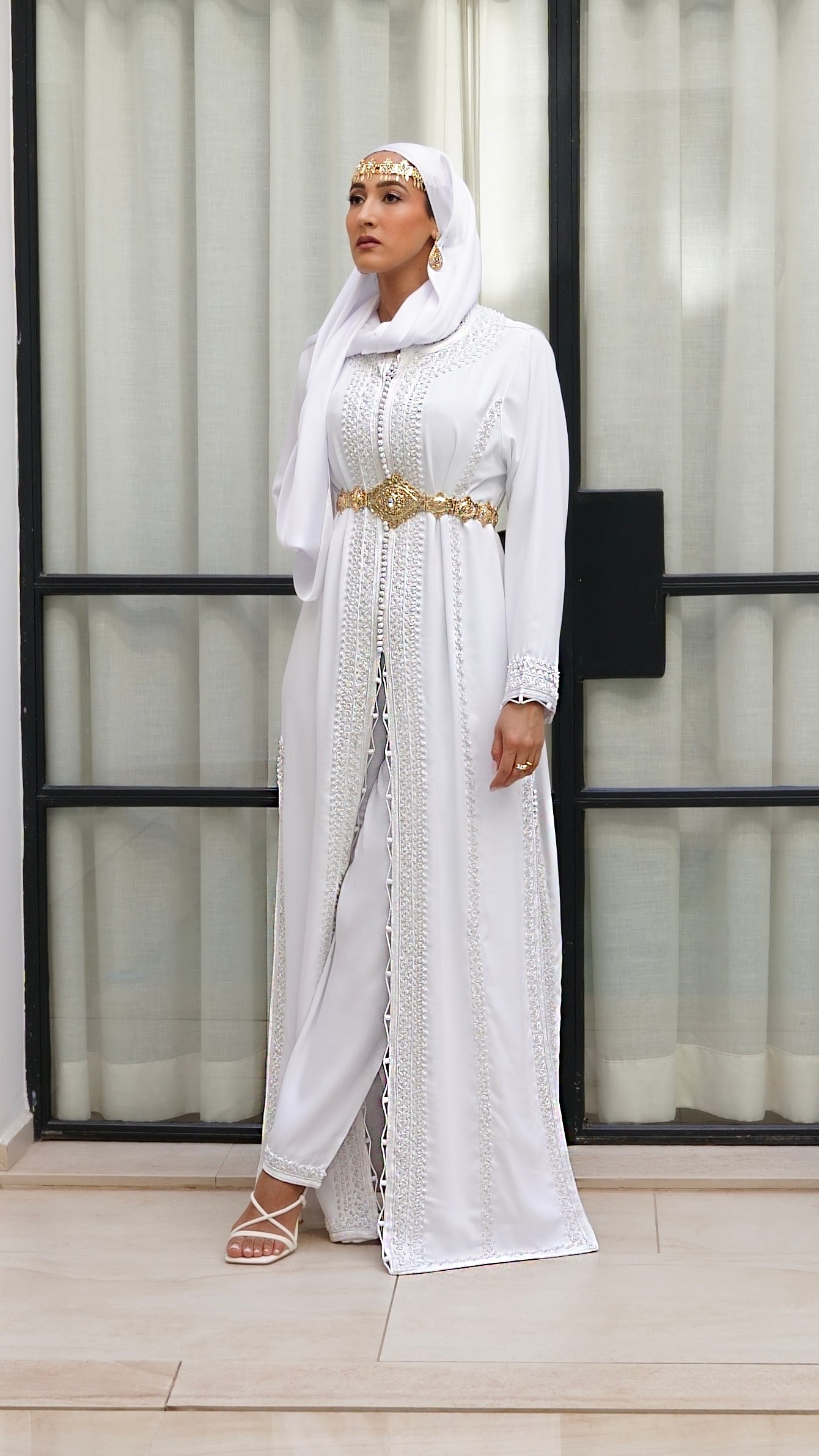 Vue en pied du caftan Rawiya blanc immaculé porté avec son pantalon fluide. Une tenue élégante, moderne et mastour, idéale pour un mariage civil. Création Beldyness.