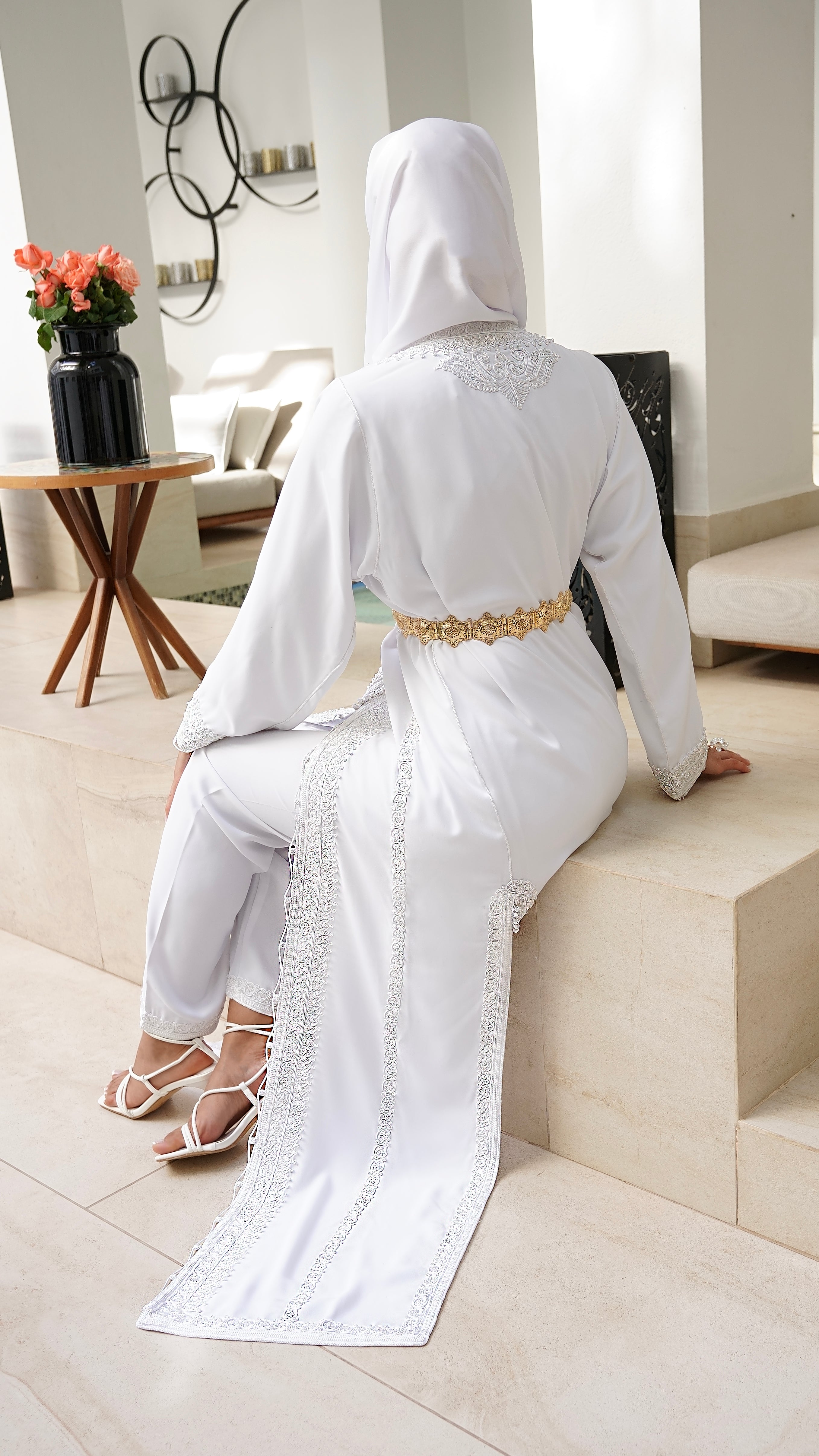 Vue de dos du caftan blanc Rawiya, soulignant le tombé majestueux du crêpe lourd sur les marches et la coupe fluide de l'ensemble pantalon. Signé Beldyness.