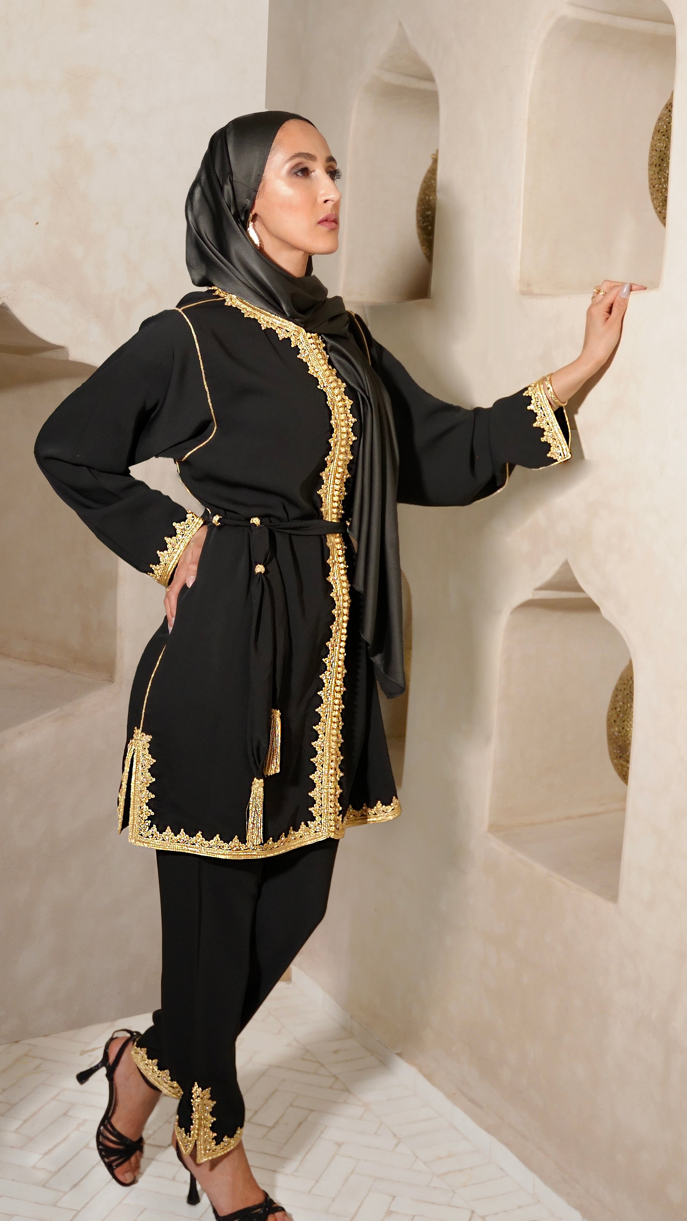 Femme portant le Jabador Johar noir en ensemble pantalon. Tenue de soirée marocaine haut de gamme, sublimée par des broderies dorées et un perlage minutieux. Création Modest Fashion Beldyness.