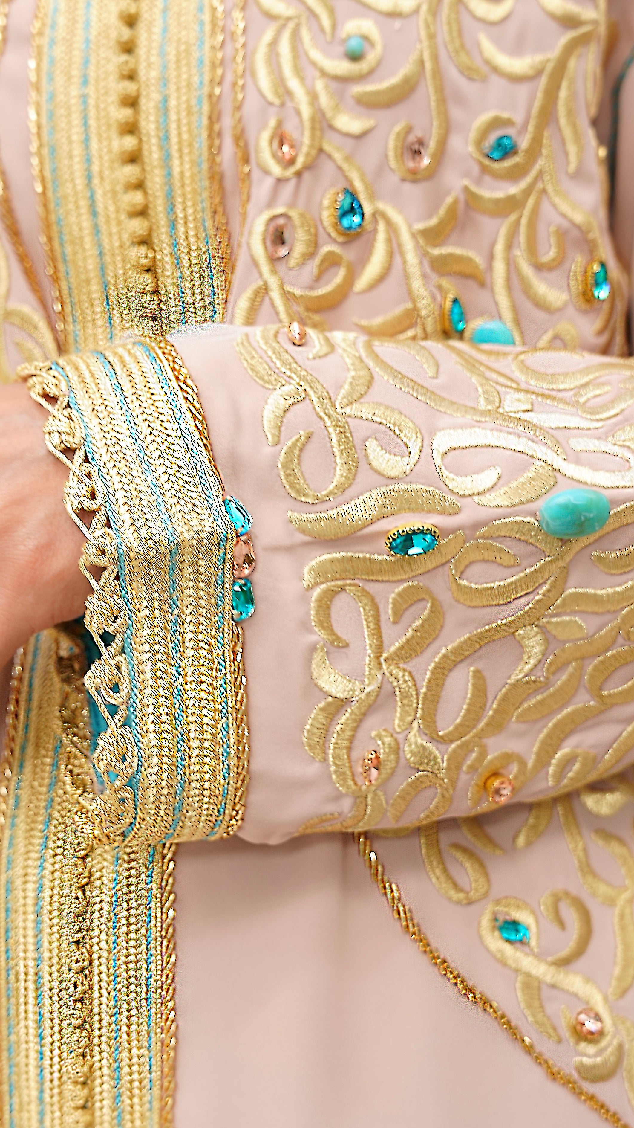 Gros plan sur le travail d'orfèvrerie du Caftan Aaliya : broderies dorées en relief et incrustations de pierres turquoise sur la manche. Finitions artisanales