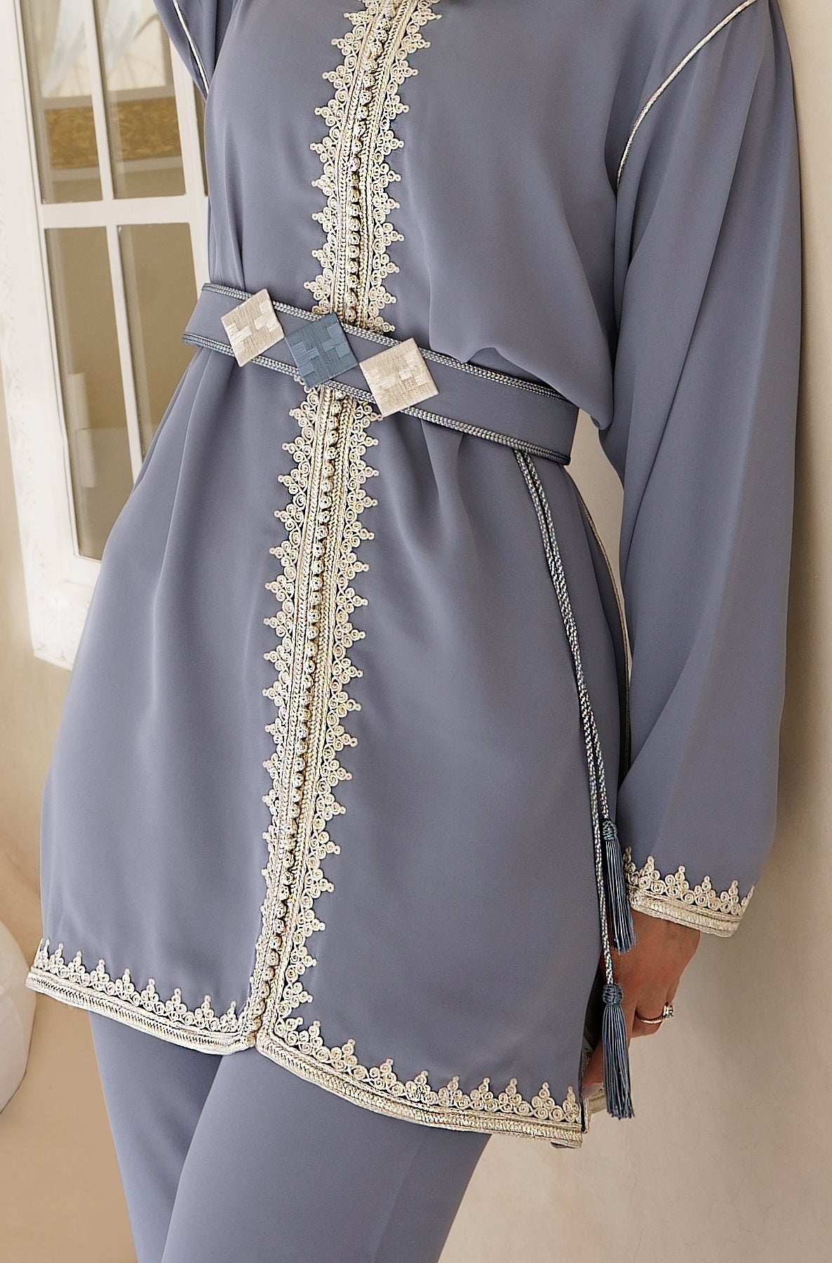 Gros plan sur les finitions artisanales du Jabador Sahar. Détail de la ceinture géométrique texturée, des cordons à pompons et de la minutieuse broderie ton sur ton. Un savoir-faire de Haute Facture.