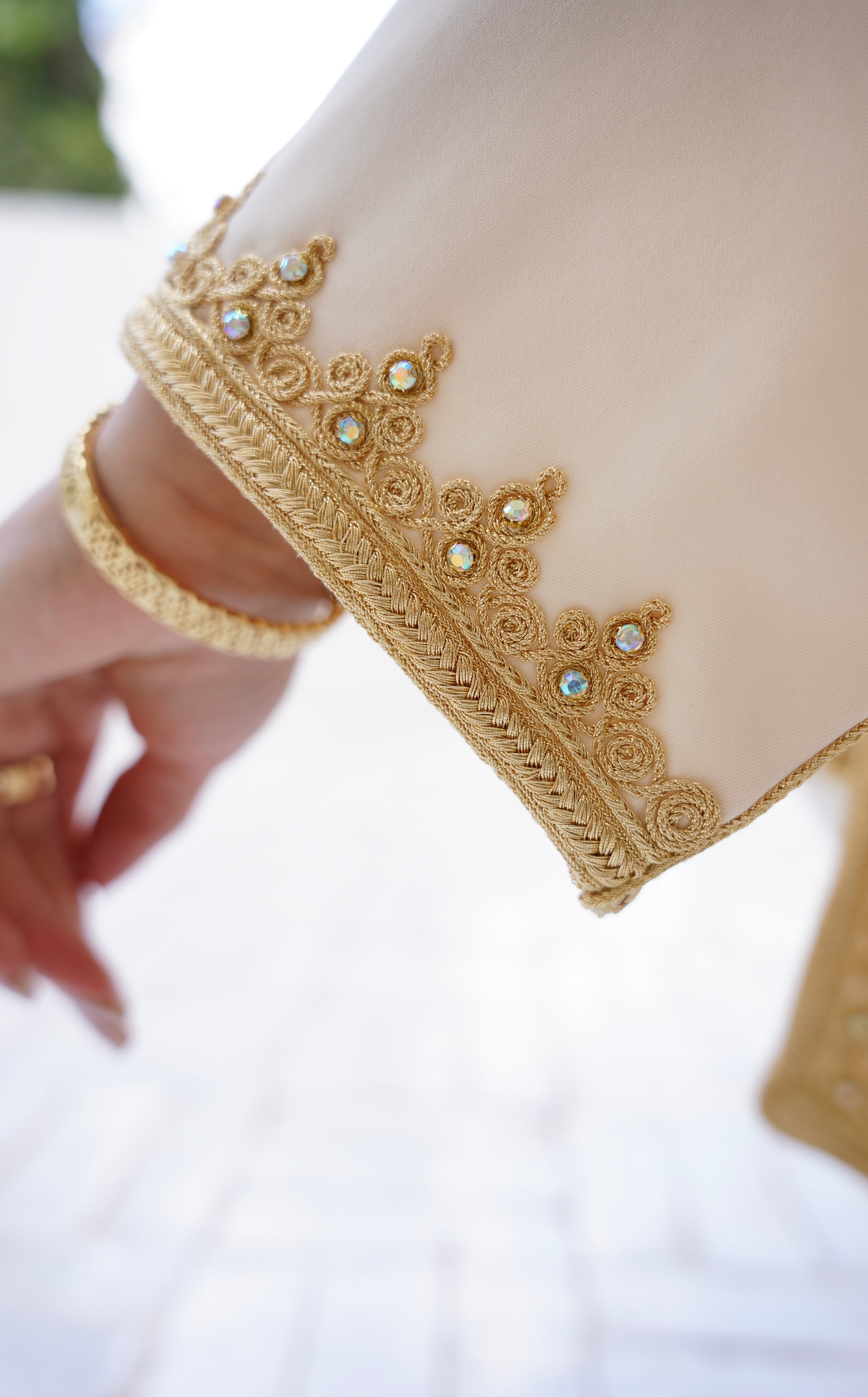 Gros plan sur les finitions artisanales de la manche du Jabador Johar. Détail de la broderie maalem en fil d'or, de la sfifa traditionnelle et des incrustations de cristaux scintillants. Un savoir-faire Haute Facture signé Beldyness.