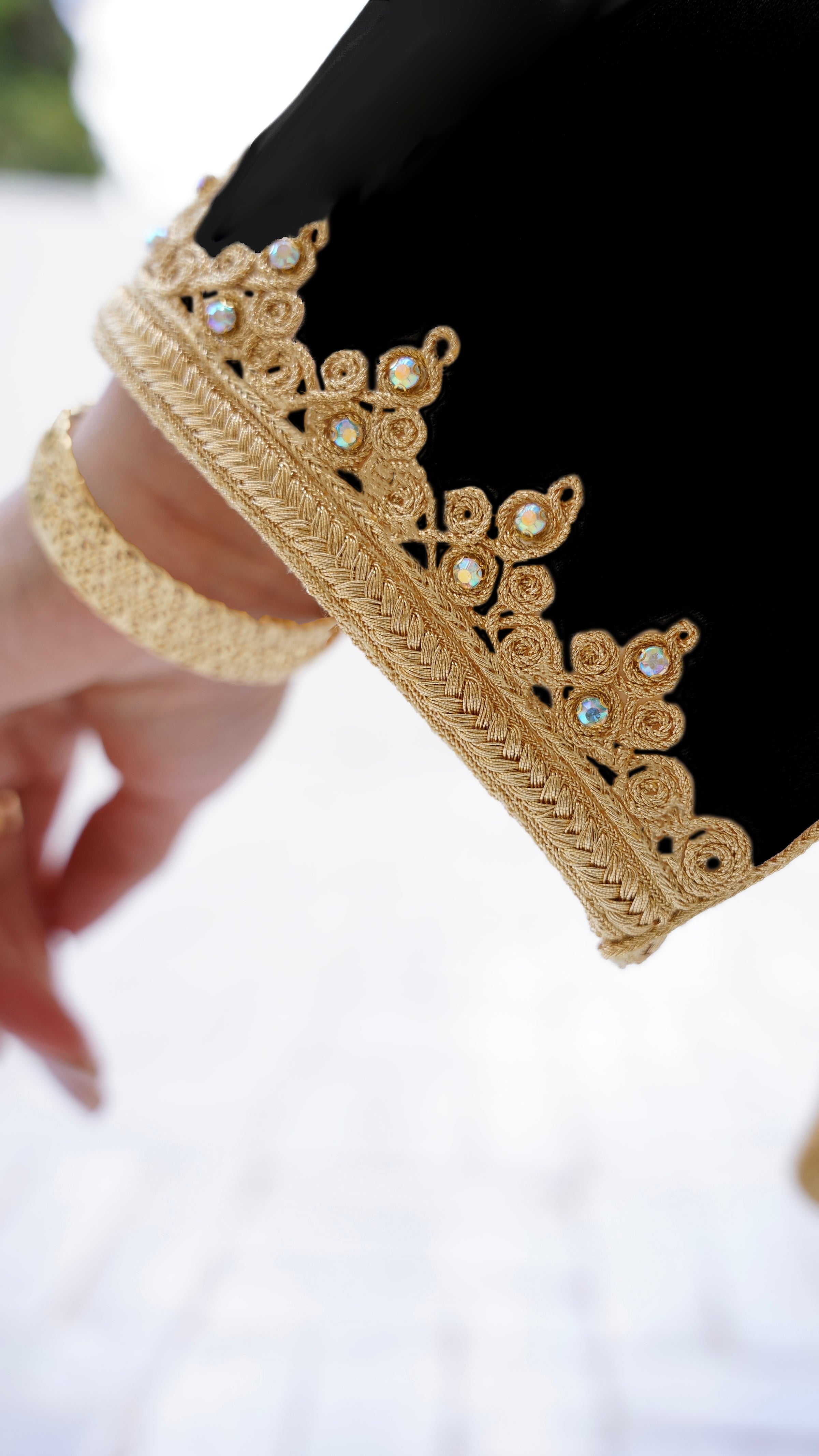 Gros plan sur les finitions artisanales de la manche du Jabador Johar noir. Détail du travail minutieux avec des broderies Maalem dorées en relief et des incrustations de pierres scintillantes. Savoir-faire de Haute Facture signé Beldyness.