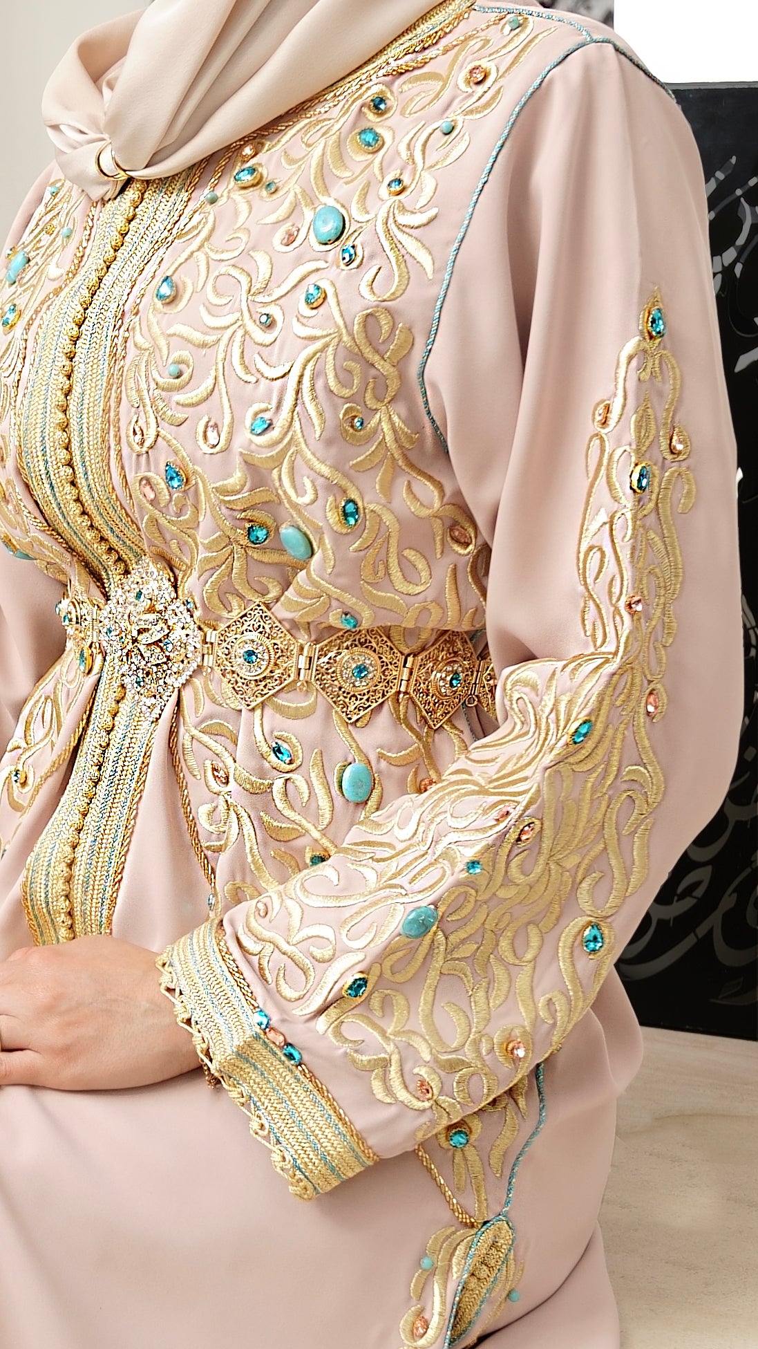 Gros plan sur la manche du caftan Aaliya beige, ornée de broderies dorées complexes et perles turquoise. Travail de finition haute couture signé Beldyness.