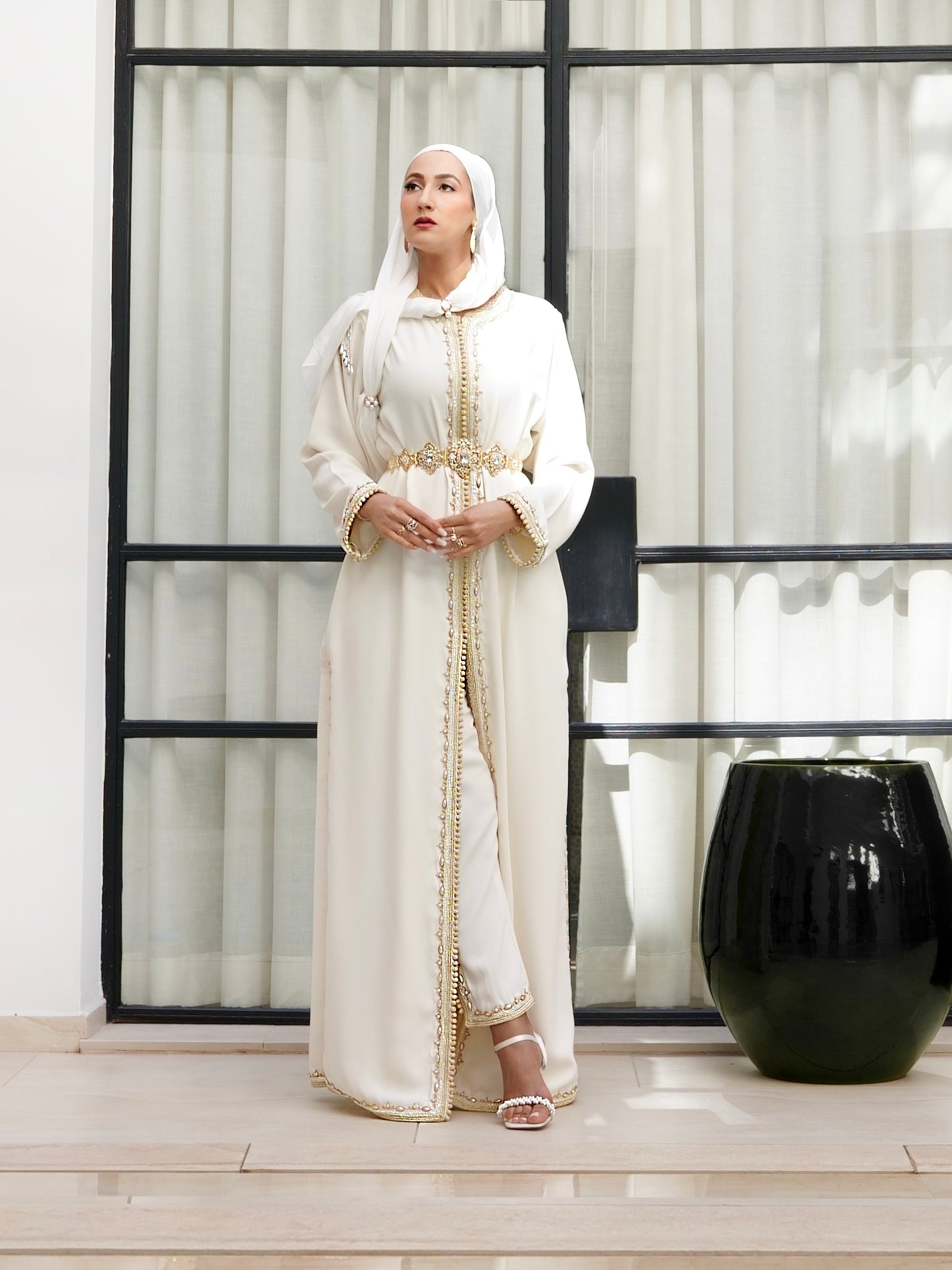 Caftan Azhar ivoire et or porté debout, révélant un ensemble pantalon moderne. Tenue de mariage marocaine avec perlage artisanal, signée Beldyness.