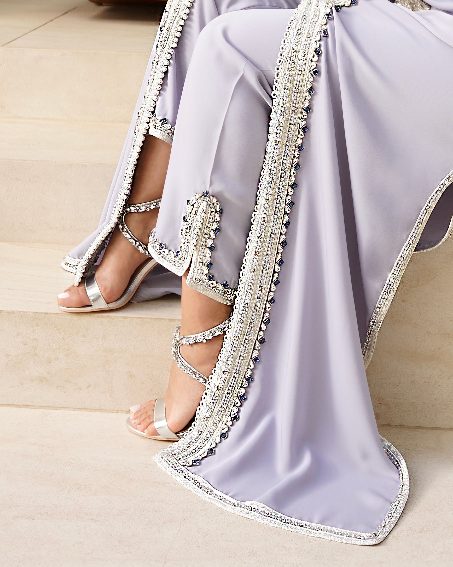 Gros plan sur la coupe pantalon et le bas du caftan Jawhara. Détail des finitions d'exception avec sfifa argentée incrustée de pierres, garantissant une élégance 100% mastour